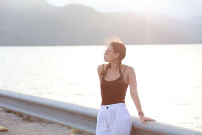 Young woman looking at sea against sky