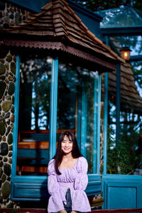 Portrait of smiling woman standing against built structure