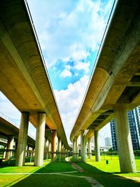 Low angle view of bridges over field against cloudy sky