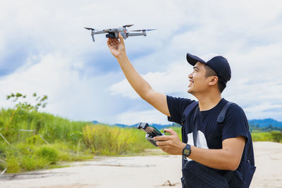 Smiling man holding drone against sky