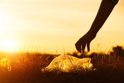 Low section of woman standing on field against sky during sunset