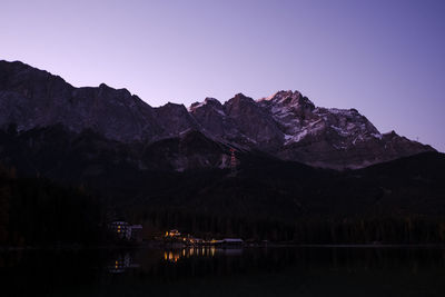 Scenic view of lake and mountains against clear sky at dusk