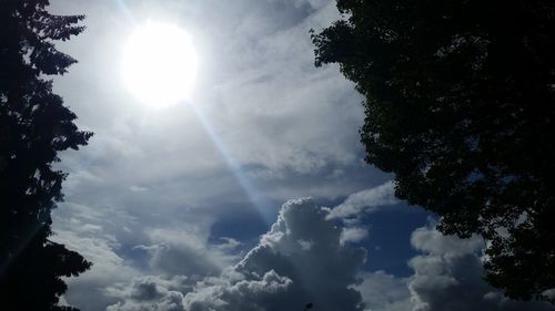 Low angle view of sunlight streaming through clouds