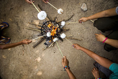 High angle view of people roasting marshmallows on bonfire