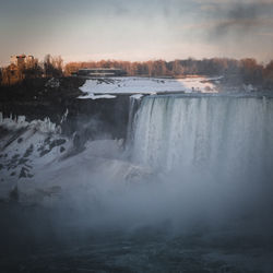 Scenic view of waterfall against sky during winter