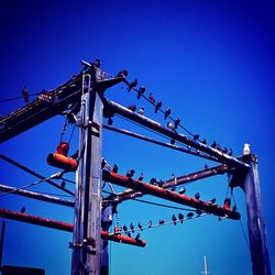 Low angle view of crane against clear blue sky