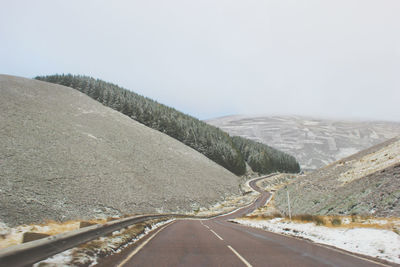 Country road by mountain against sky