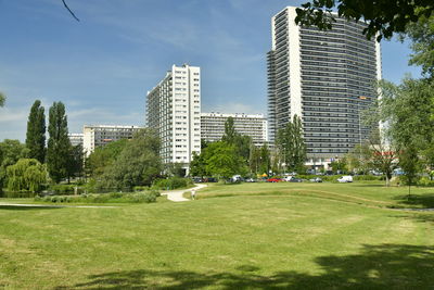Park by buildings in city against sky
