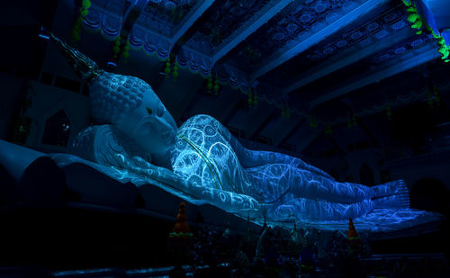 Low angle view of statue against illuminated building at night