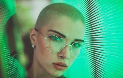 Portrait of young woman with shaved head standing against abstract backgrounds