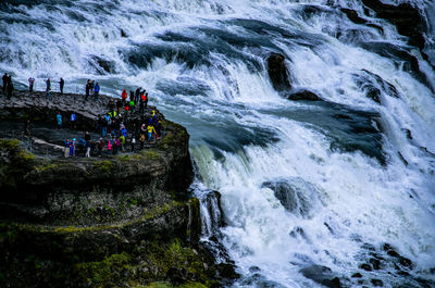 Group of people on rock against waterfall