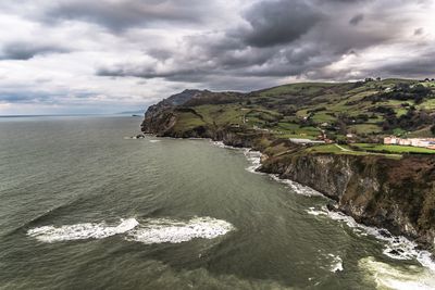 High angle view of coastal rocks against cloudy sky