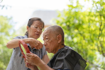 Wife cutting hair of husband outdoors