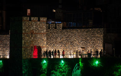 Illuminated lights hanging on wall in city at night