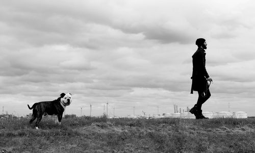 Full length of man with dog standing on field against sky