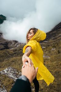 Cropped image of man holding woman hand on field during foggy weather