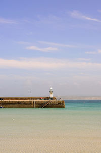 Lighthouse by sea against sky