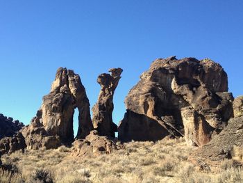 Low angle view of rock formations against clear blue sky