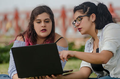 Friends working on laptop at park