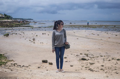 Fashionable young woman standing on beach