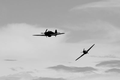 Low angle view of airplane flying in cloudy sky