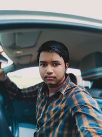 Portrait of young man sitting in car