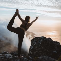 Woman photographing on rock against sky