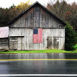 American flag on wooden house by wet road