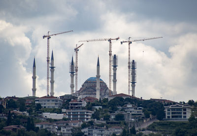 Cranes in city against sky