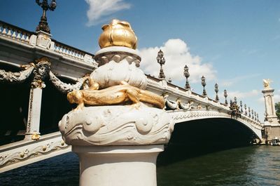 Statue of bridge over water against sky