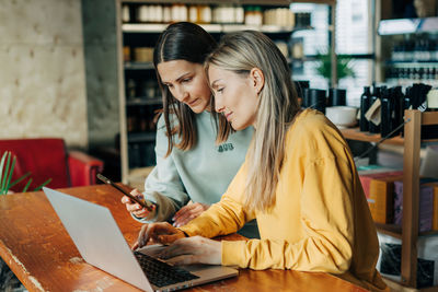 Young woman using laptop while sitting on table