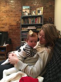 Mother and daughter sitting on sofa at home