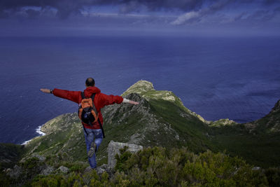 High angle view of man standing on cliff by sea