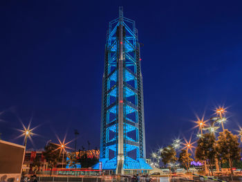 Low angle view of illuminated buildings against blue sky