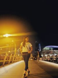 Woman with umbrella on illuminated city at night