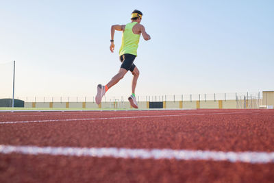 Young man trains running on new and red tracks