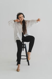 Portrait of young woman with arms crossed against white background