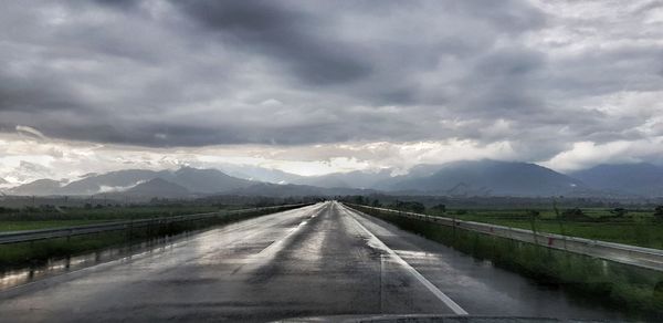 Road leading towards mountains against sky