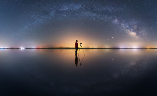 Man standing in lake against sky at night