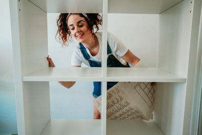 Portrait of smiling young woman standing against wall at home