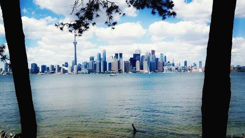 Cityscape by sea against sky