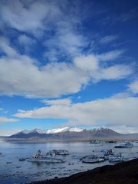 Scenic view of sea by snowcapped mountain against sky