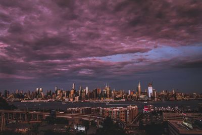 Illuminated cityscape against cloudy sky