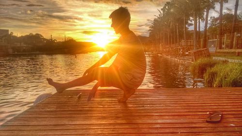 Woman sitting on bench at beach during sunset