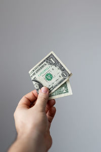 Cropped hand holding paper currency against gray background