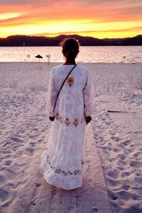 Portrait of young woman standing at beach during sunset