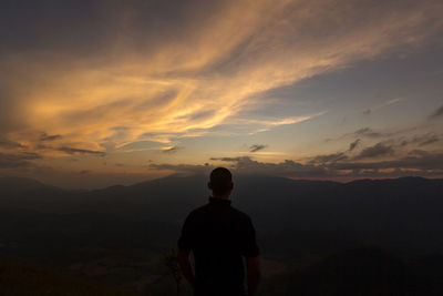 Rear view of man standing on mountain against sky