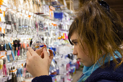 Side view of young woman looking at galileo thermometer at store