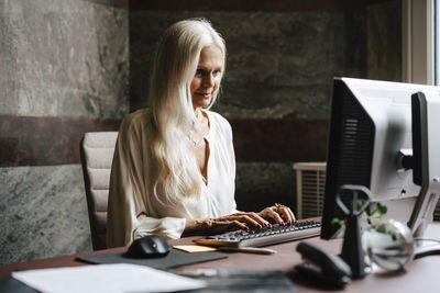 Young woman using laptop at desk in office