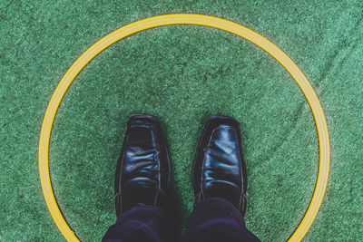 Low section of man wearing shoes standing on green circle